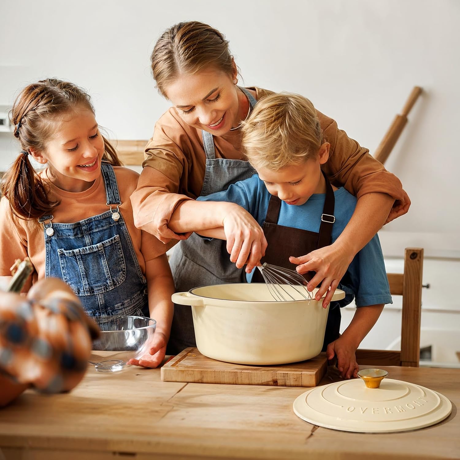 Cream white enameled cast iron Dutch oven with matching lid, displayed with included cookbook and cotton potholders — view 5